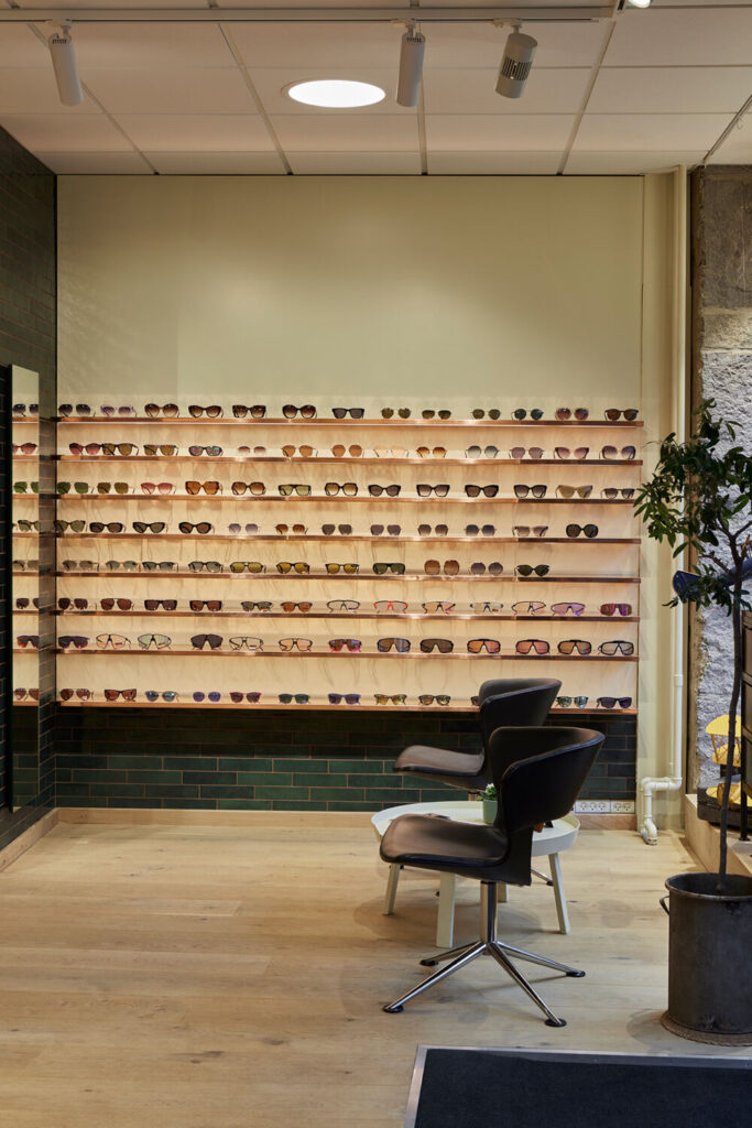 Egetræsreoler hos Optik Nicolai’s i Roskilde med glashylder og kobberdetaljer, specialinventar og opbevaringsløsninger i butikken.