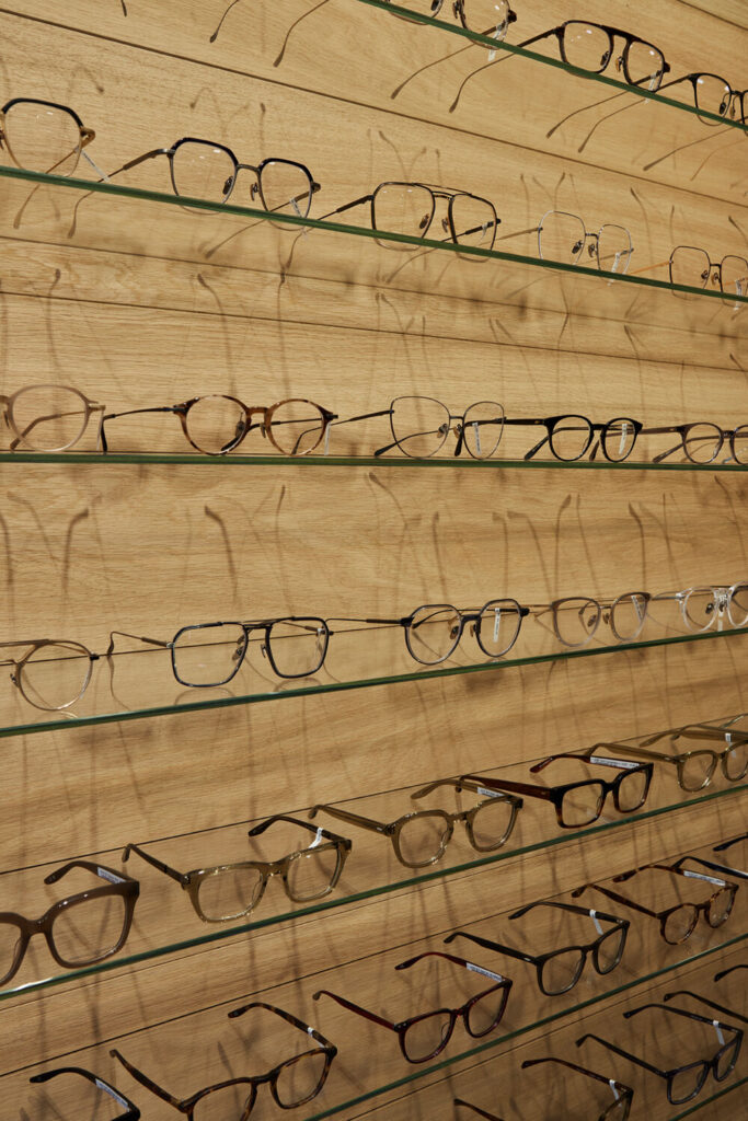 Egetræsreoler hos Optik Nicolai’s i Roskilde med glashylder og kobberdetaljer, specialinventar og opbevaringsløsninger i butikken.